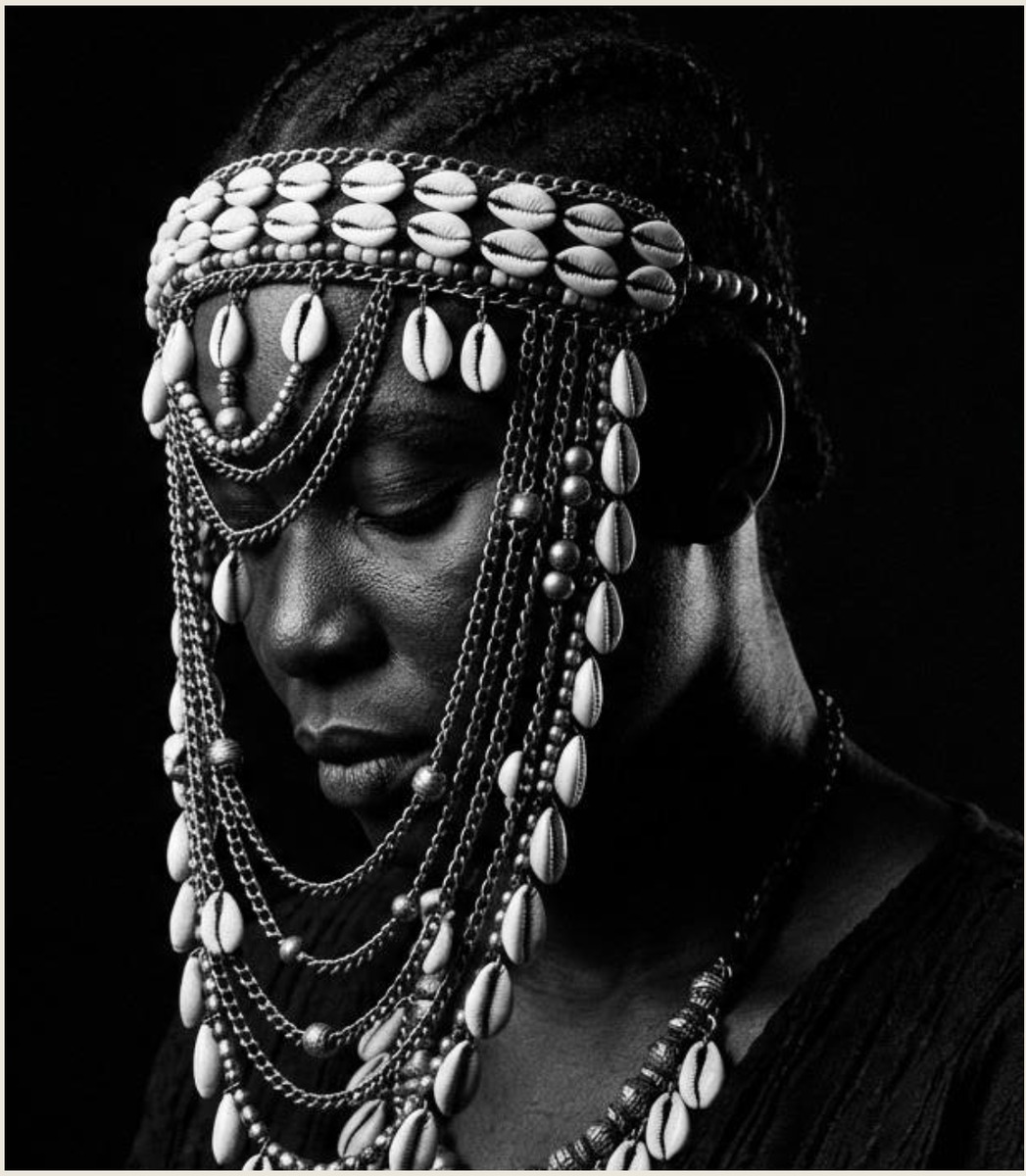 Iya Laje — monochrome portrait of a woman adorned in cowries, chains and beads